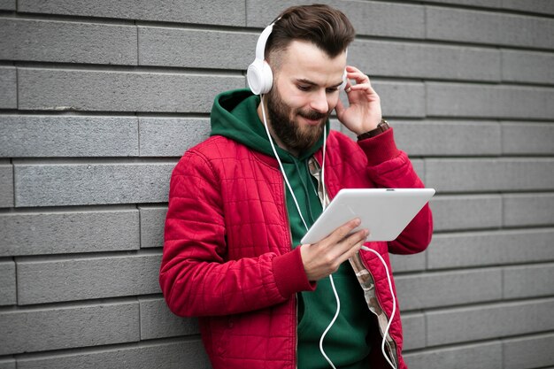 Side view guy with headphones and tablet