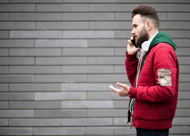 Foto gratuita ragazzo di vista laterale con le cuffie che parla al telefono