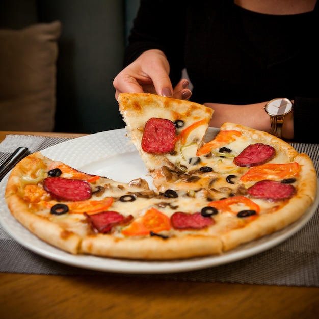 Вид сбоку пицца с колбасой на белом фоне