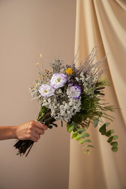 Free photo side view hand holding beautiful flowers