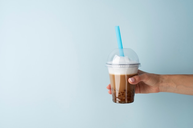 Free photo side view hand holding bubble tea