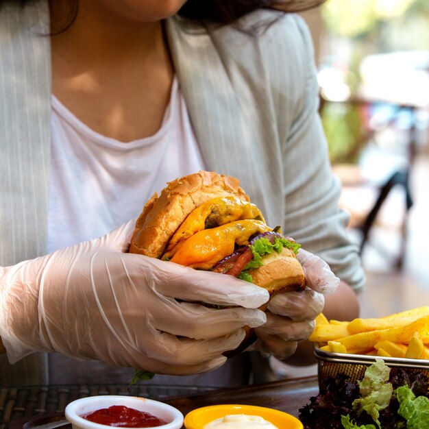 ビーフカツレツチーズとトマトのハンバーガーを持っている手の側面図