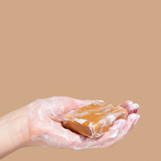 Side view of hand holding foamy soap with copy space