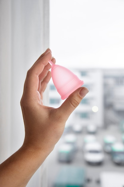 Side view hand holding pink menstrual cup