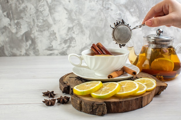 Side view of hand holding tea pot black tea in a white cup on white table