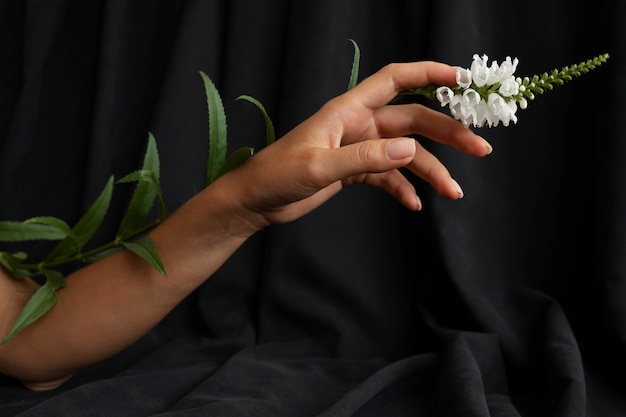 Free photo side view hand posing with flower