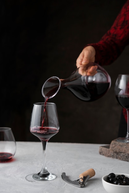 Free photo side view hand pouring red wine