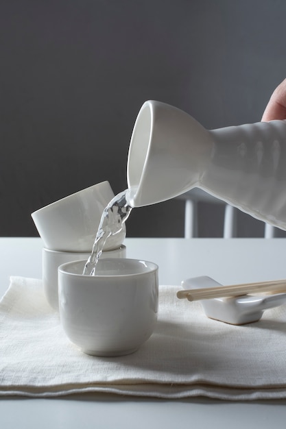 Side view hand pouring sake drink