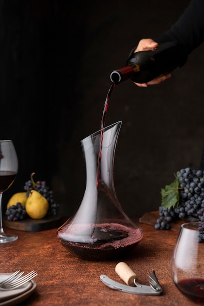 Free photo side view hand pouring wine in carafe