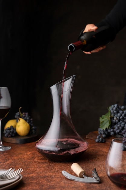 Вид сбоку рука наливает вино в графин