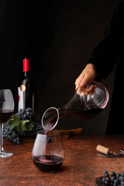 Вид сбоку рука наливает вино в бокал