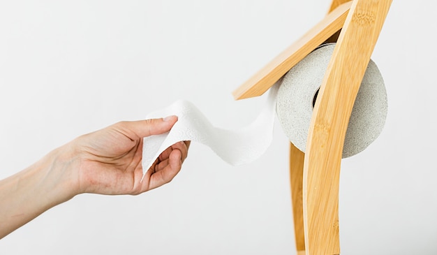 Side view hand pulling toilet paper