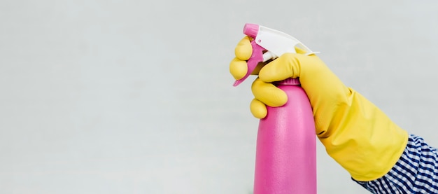 Side view of hand in rubber glove holding cleaning product