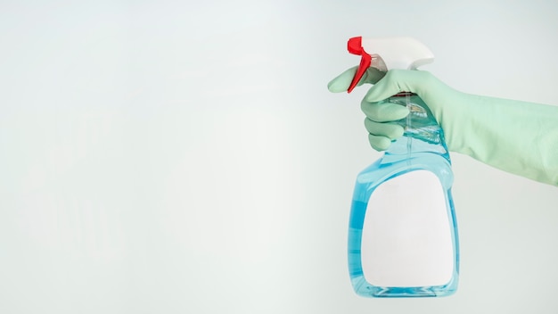 Free photo side view of hand with glove holding cleaning solution