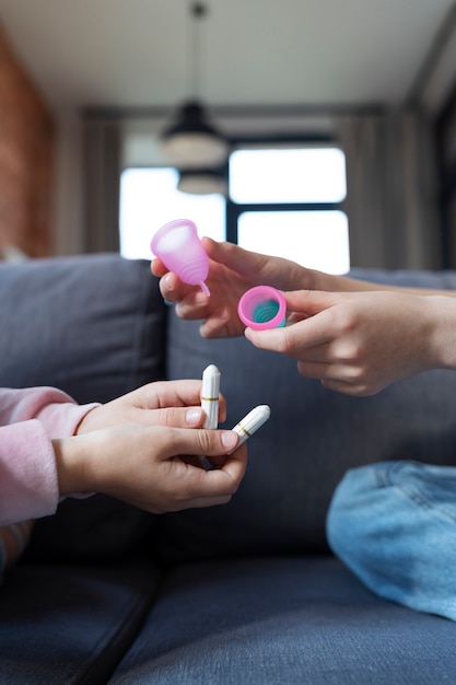 Side view hands holding menstrual cups and tampons