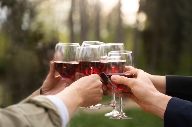 Mani di vista laterale che tengono bicchieri di vino