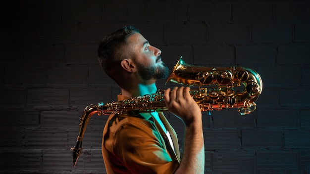 Free photo side view of handsome male musician holding saxophone