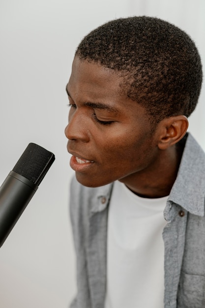 Vista laterale del musicista maschio bello che canta con il microfono