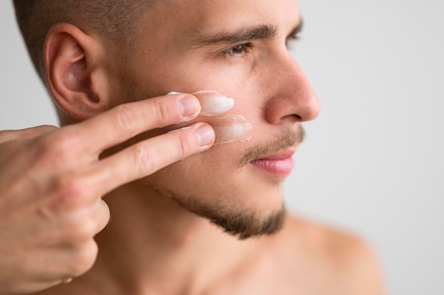 Side view of handsome man applying cream on his face