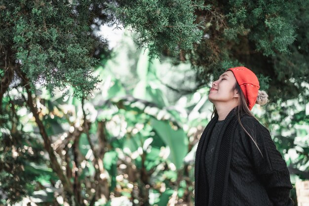 冬の衣装で幸せなアジアの若い女性の側面図コピースペース休暇と旅行のコンセプトで森の屋外で新鮮な空気を呼吸してリラックス