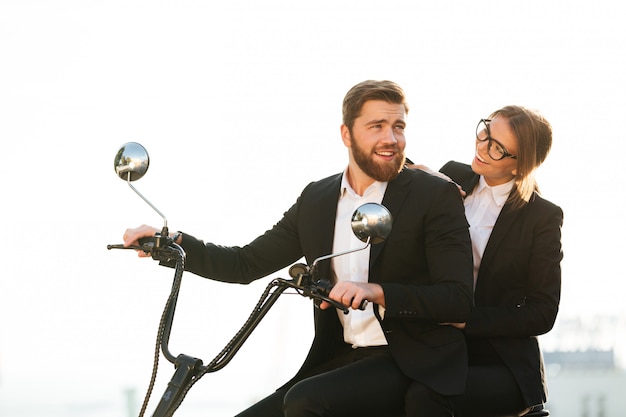 Вид сбоку счастливая пара в костюмах едет на мотоцикле