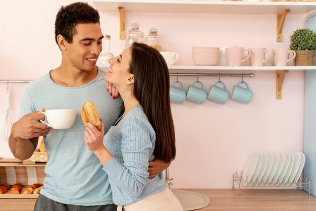 Вид сбоку счастливая пара с пончиком и чашкой
