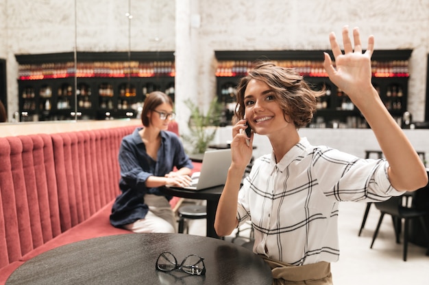 Foto gratuita vista laterale della donna riccia felice che parla dal telefono