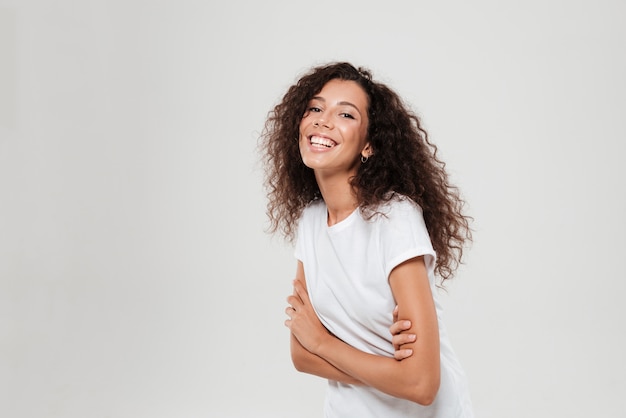 Side view of happy curly woman with crossed arms