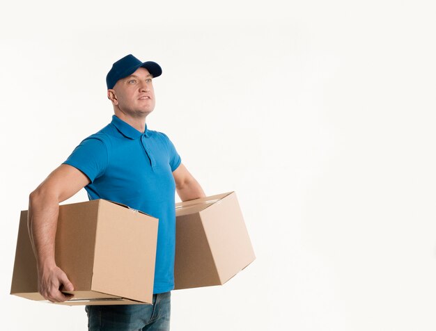 Side view of happy delivery man holding cardboard boxes