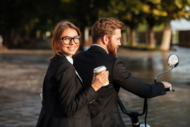 Side view of happy elegant couple rides on modern motorbike