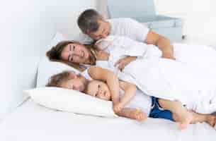 Бесплатное фото Вид сбоку счастливая семья лежит в постели