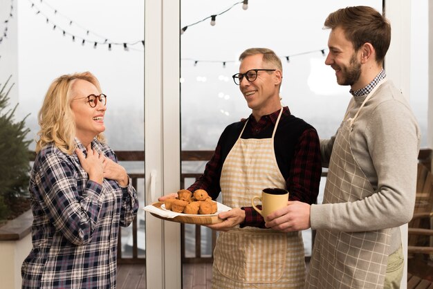 Side view of happy family with muffins and cup