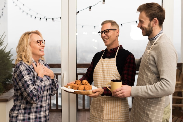 Side view of happy family with muffins and cup