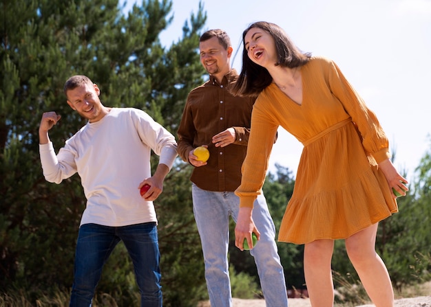 Free photo side view happy friends playing game outdoors