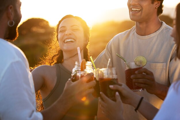 外で飲み物を飲みながら幸せな友達の側面図