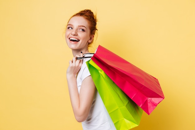 Side view of happy ginger woman holding packets on shoulder