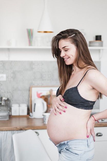 Side view of happy pregnant woman standing in kitchen