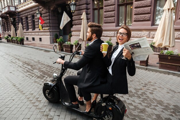 Side view of happy stylish couple rides on modern motorbike