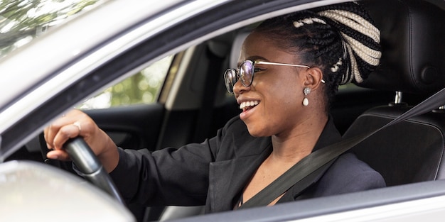 Vista laterale della donna felice alla guida della propria auto