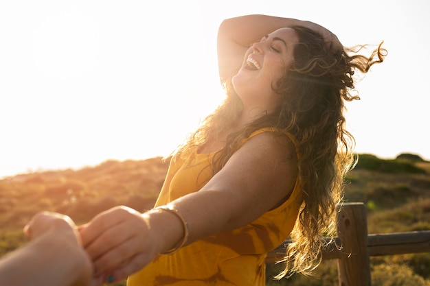 Side view of happy woman holding hands with photographer