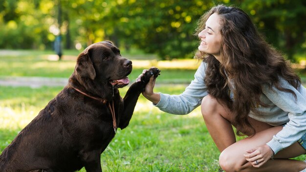 彼女の犬と遊んでいる幸せな女性の側面図