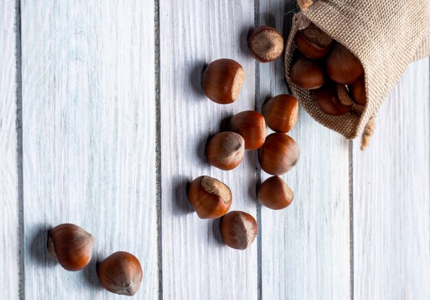 Side view of hazelnuts scattered from a sack on wooden rustic