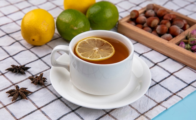 Фундук с грецкими орехами, вид сбоку и чашка чая с лимоном на клетчатом полотенце
