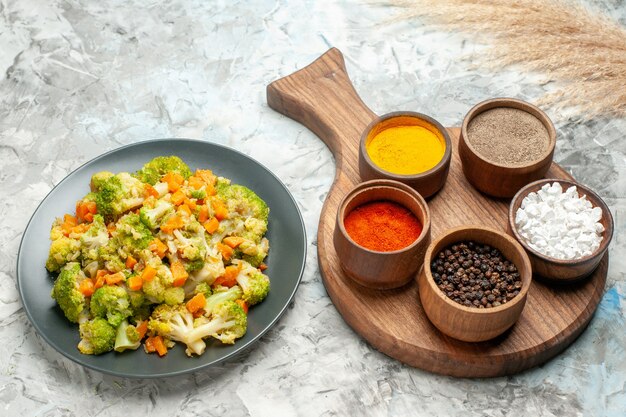 Side view of healthy vegetable salad different spices on cutting board on white table