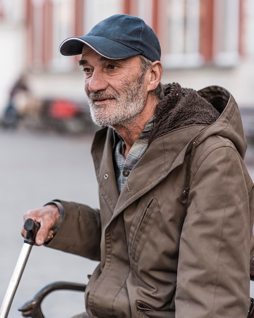 Side view of homeless man outdoors with cane