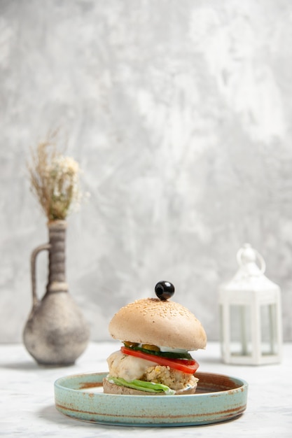 Side view of homemade delicious sandwich with black olive on a plate and accessories on stained white surface