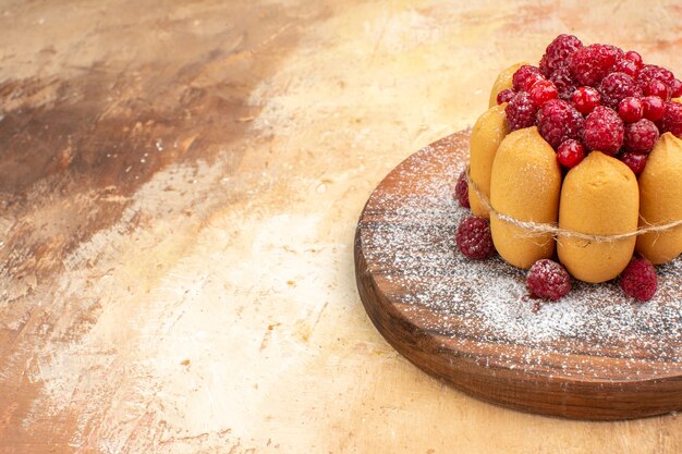 Side view of homemade soft cake with fruits on wooden cutting board on mixed color table