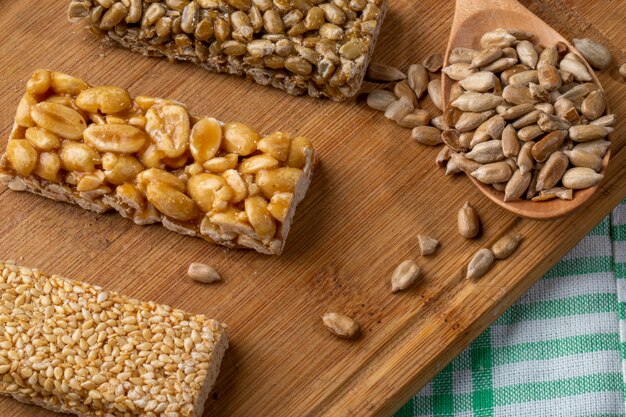 Side view of honey bars with peanuts sesame and sunflower seeds on a wooden board on rustic