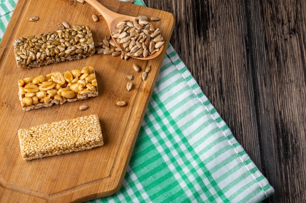 Side view of honey bars with peanuts sesame and sunflower seeds on a wooden board on rustic