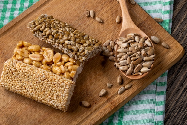 Side view of honey bars with peanuts sesame and sunflower seeds on a wooden board on rustic